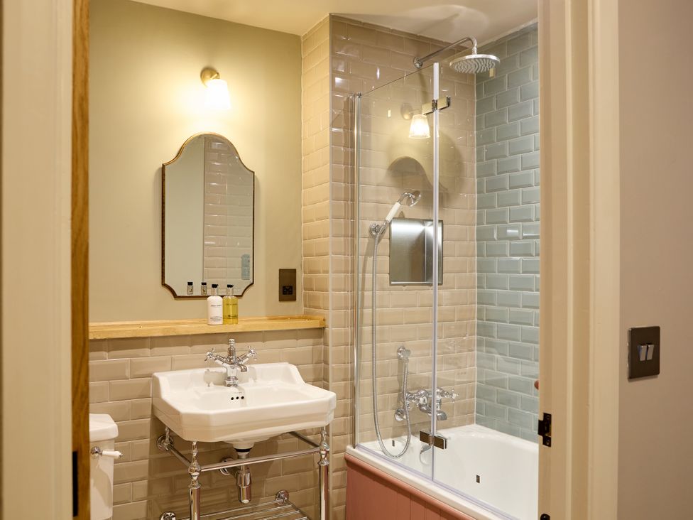 A bathroom with a sink, mirror, and shower at The Dovecote in Matlock