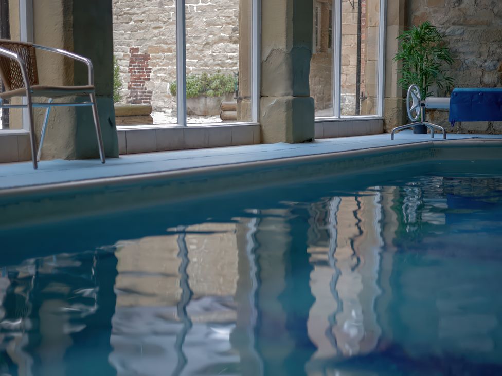An indoor pool with a chair and windows at The Dovecote in Hopton