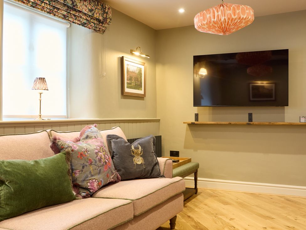 A living room with a sofa and a television at Butler's Quarters in Matlock