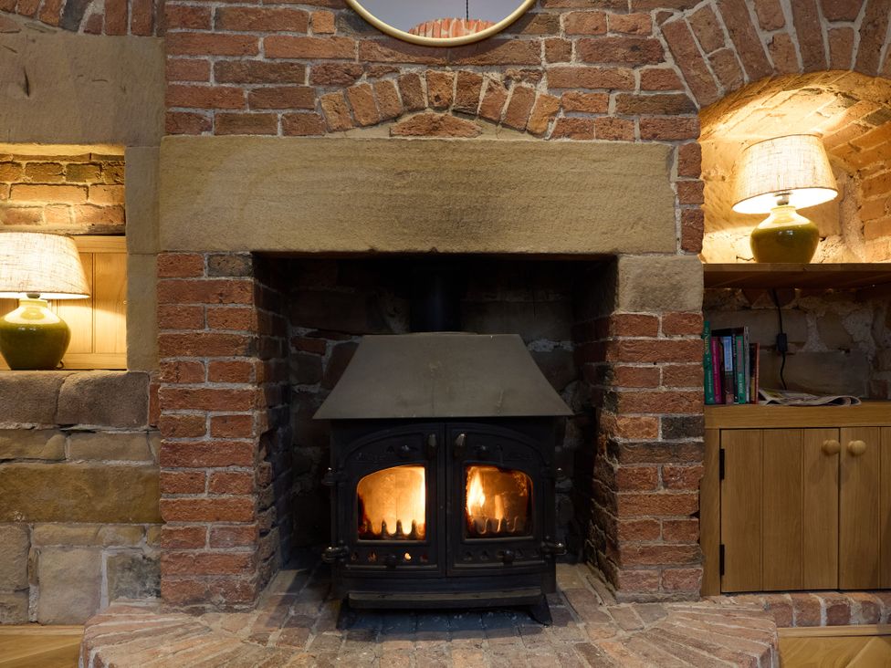 A fireplace with wood stove and lamps in a living room at Butler's Quarters in Matlock