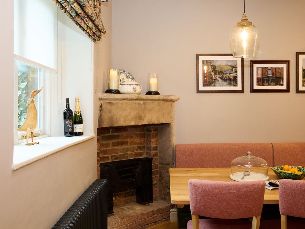 A dining room with a table and fruit bowl at Butler's Quarters in Matlock