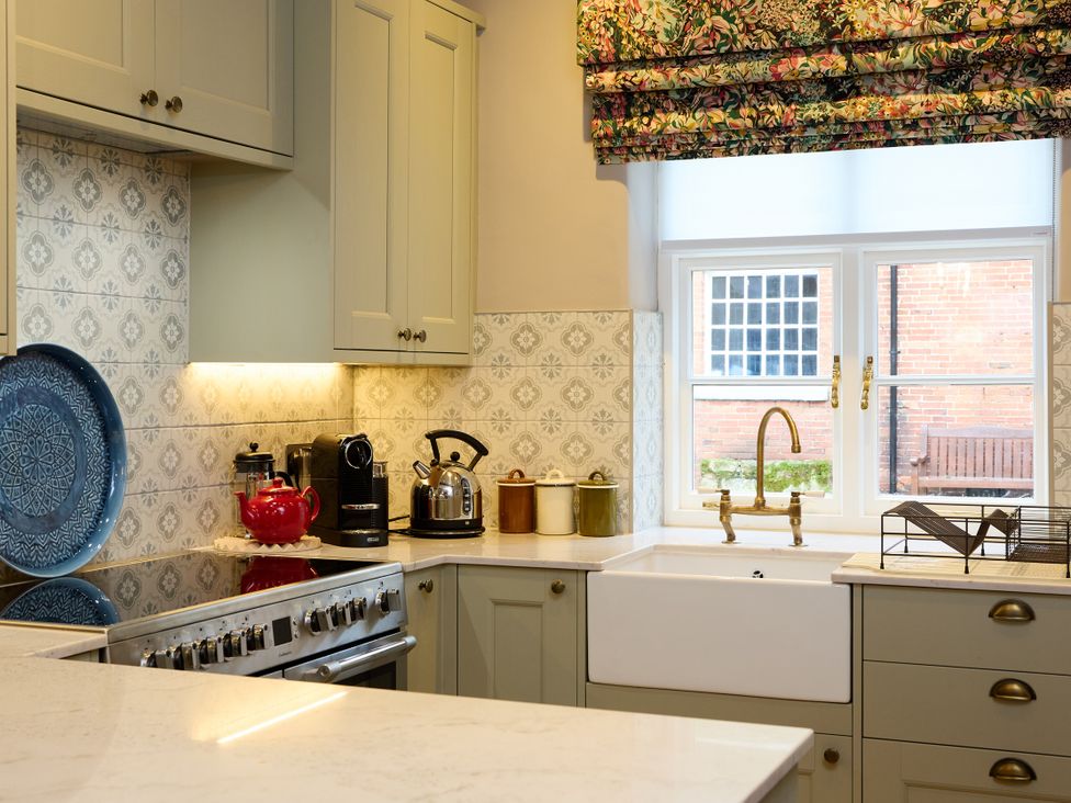 A kitchen with a sink, stove, kettle, and coffee machine at Butler's Quarters in Matlock
