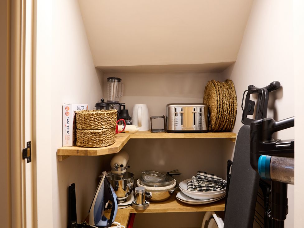 A kitchen pantry with shelves holding appliances and kitchenware at Butler's Quarters in Matlock