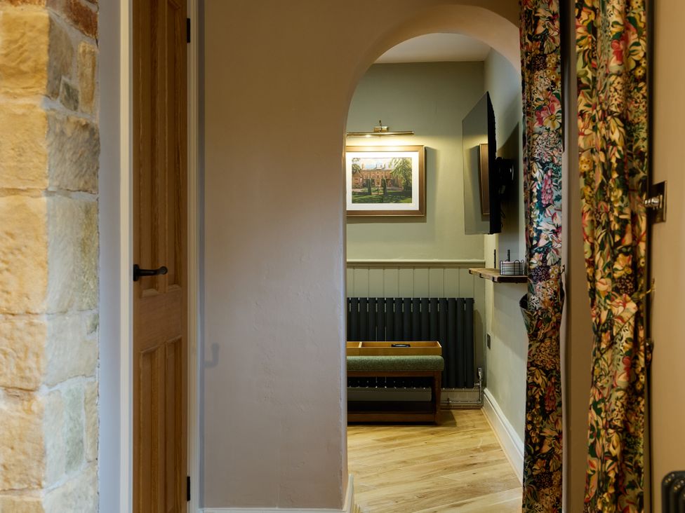 A hallway with an archway and a door at Butler's Quarters in Matlock