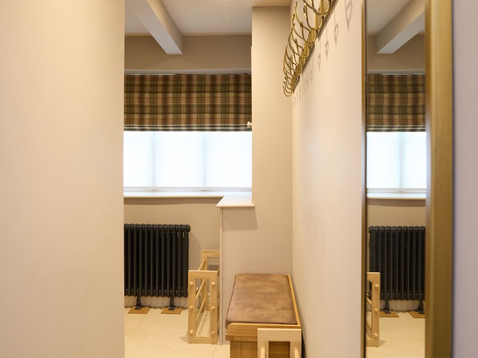 A hallway with a bench and coat hooks at Butler's Quarters in Matlock