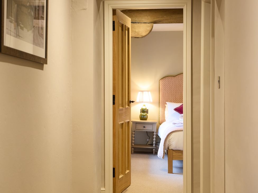 A hallway view into a bedroom with a bed and lamp at Butler's Quarters in Matlock