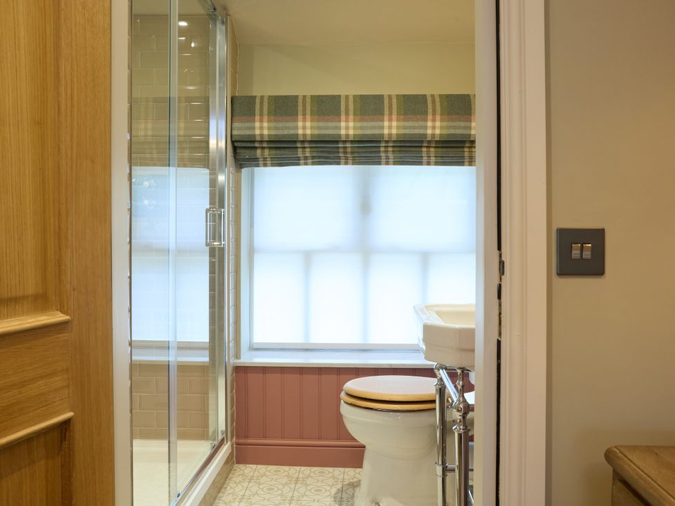 A bathroom with a shower, toilet, and sink at Butler's Quarters in Matlock