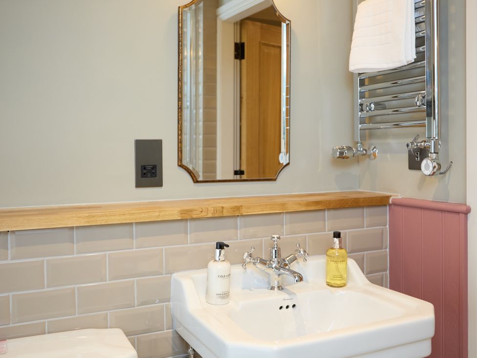 A sink with a mirror and a towel radiator at Butler's Quarters in Matlock