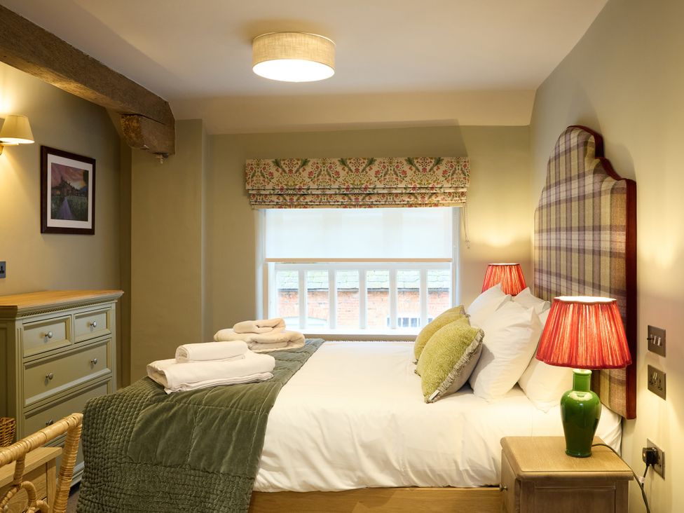 A bedroom with a bed and side tables at Butler's Quarters in Matlock