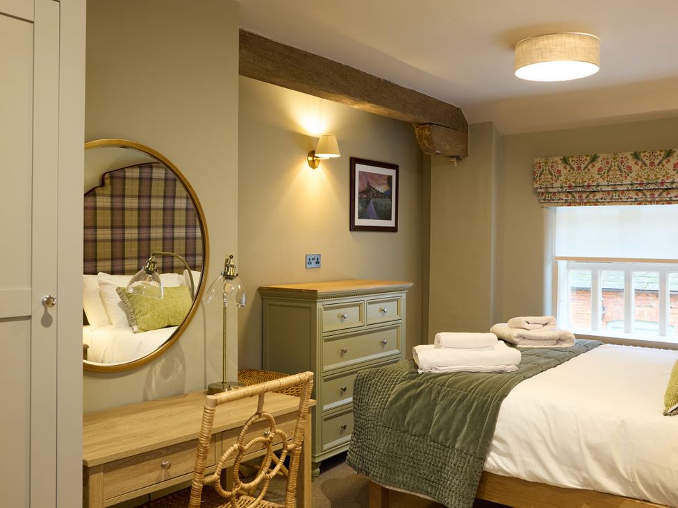 A bedroom with a bed and dresser at Butler's Quarters in Matlock