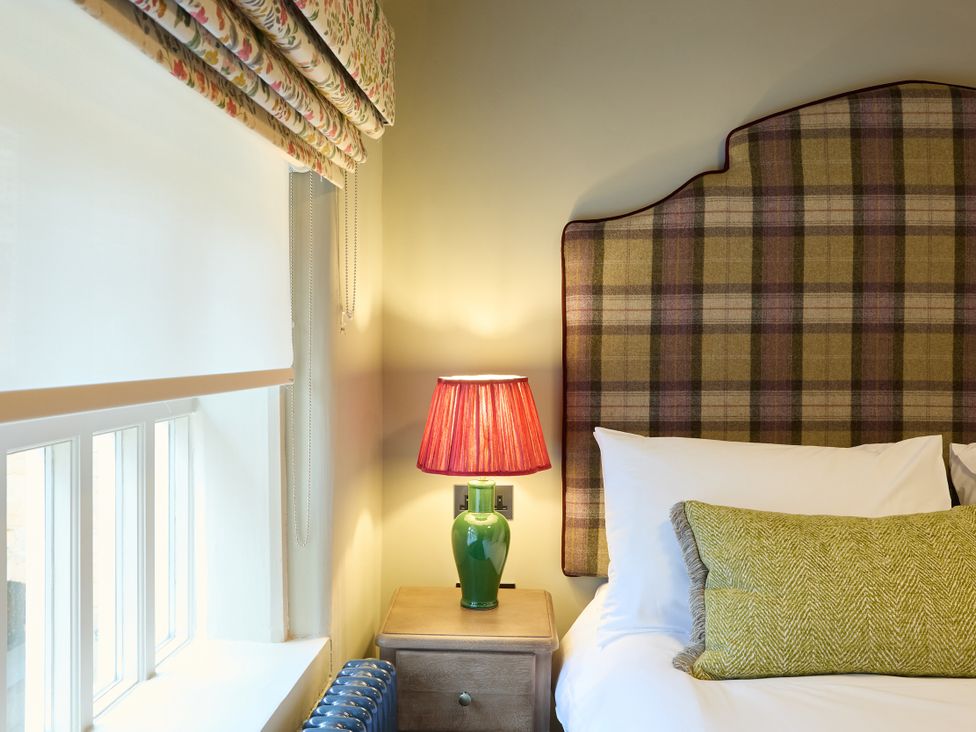 A bedroom with a bed and lamp at Butler's Quarters in Matlock