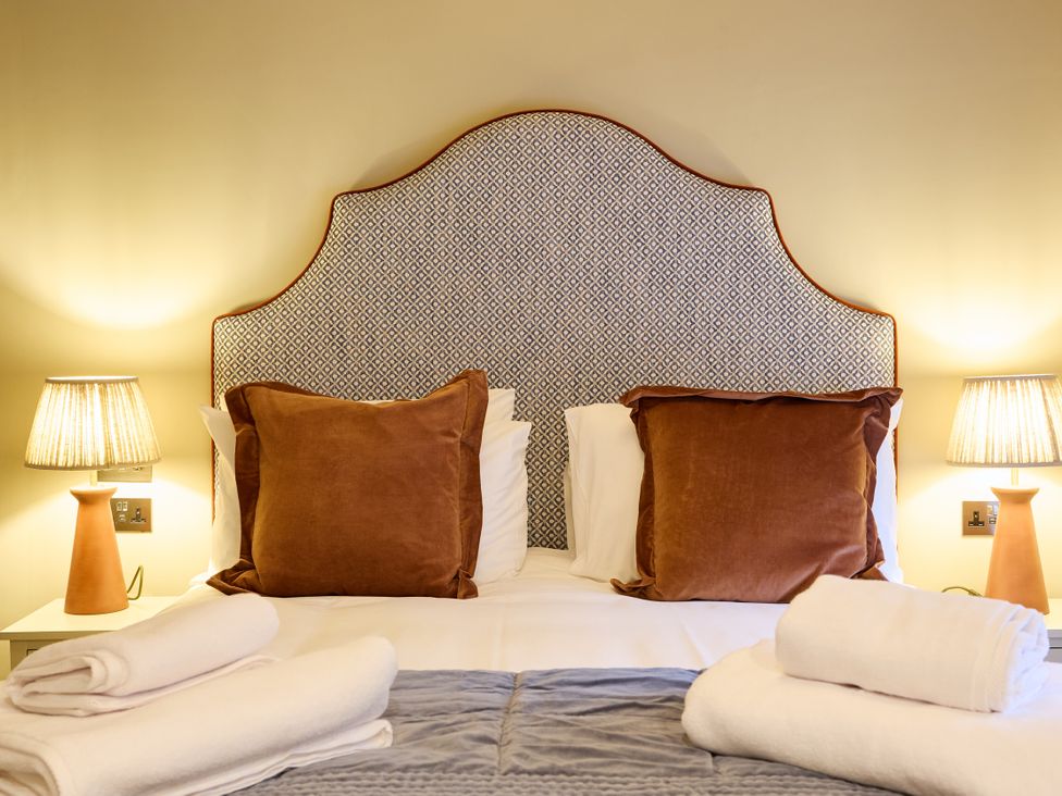 A bedroom with a bed, pillows, and lamps at Butler's Quarters in Matlock