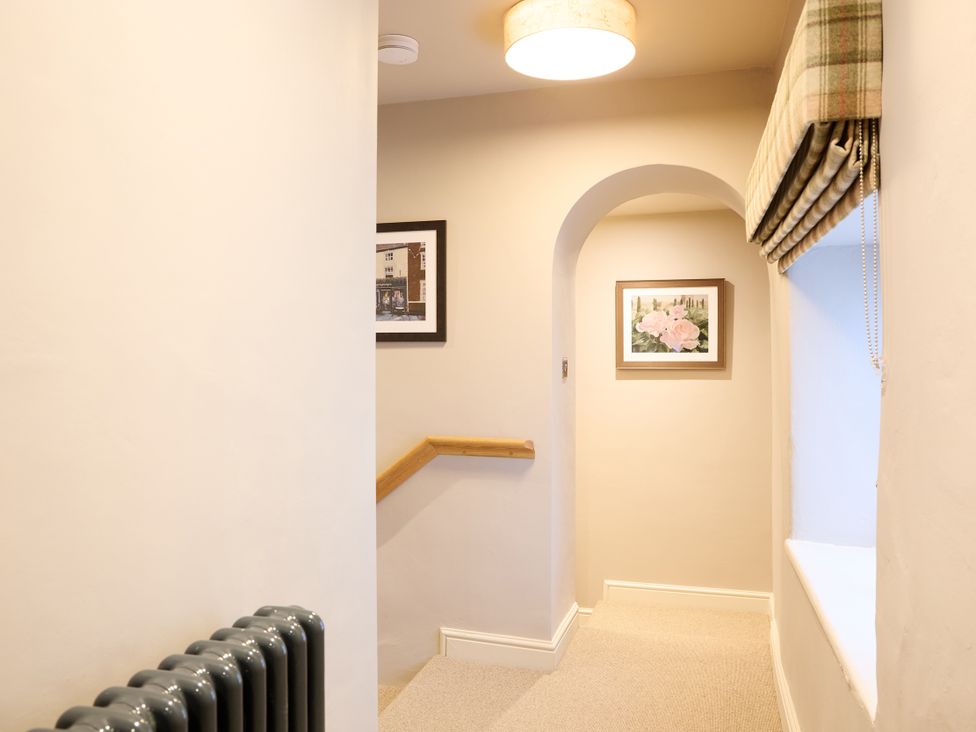 A hallway with a radiator and artwork at Butler's Quarters Matlock