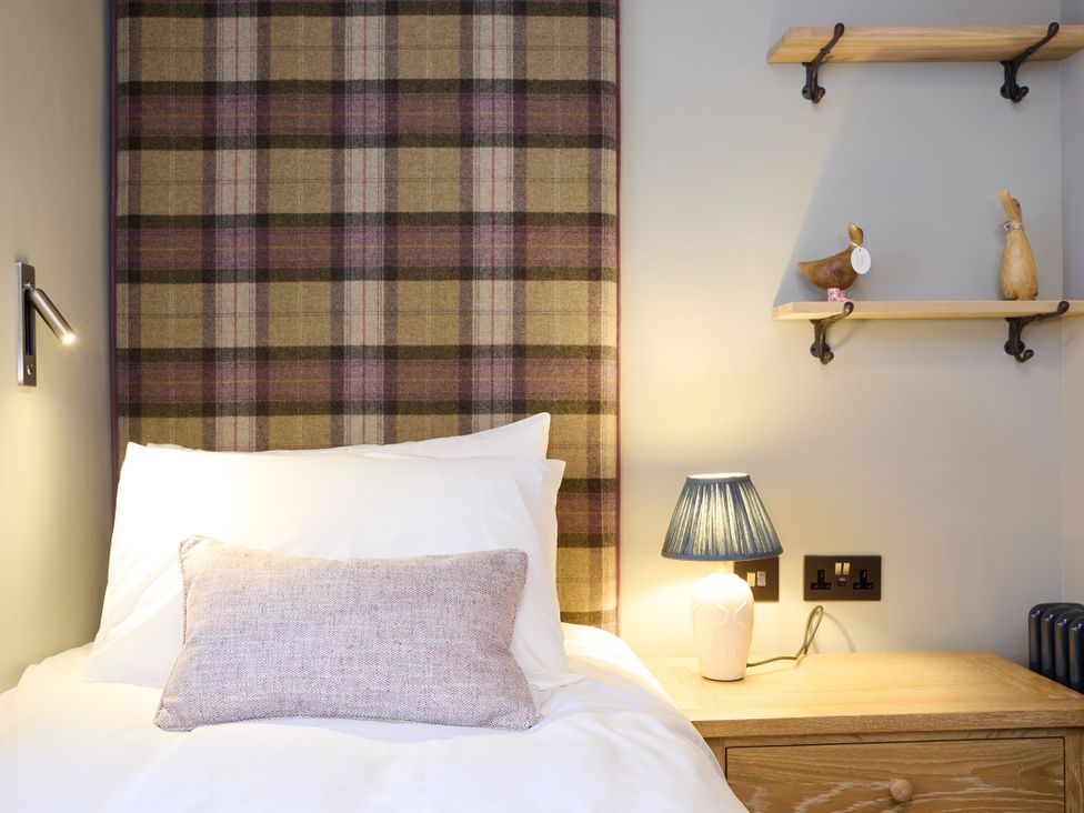 A bedroom with a bed and bedside table at Butler's Quarters in Matlock
