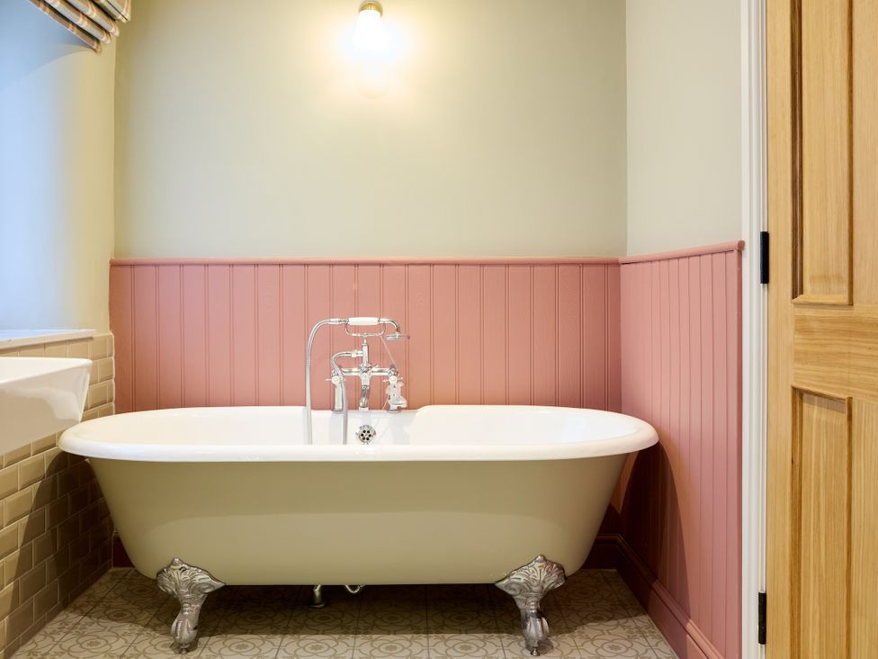 A bathroom with a bathtub and faucet at Butler's Quarters in Matlock