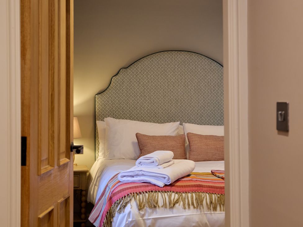 A bedroom with a bed and pillows visible at Butler's Quarters in Matlock