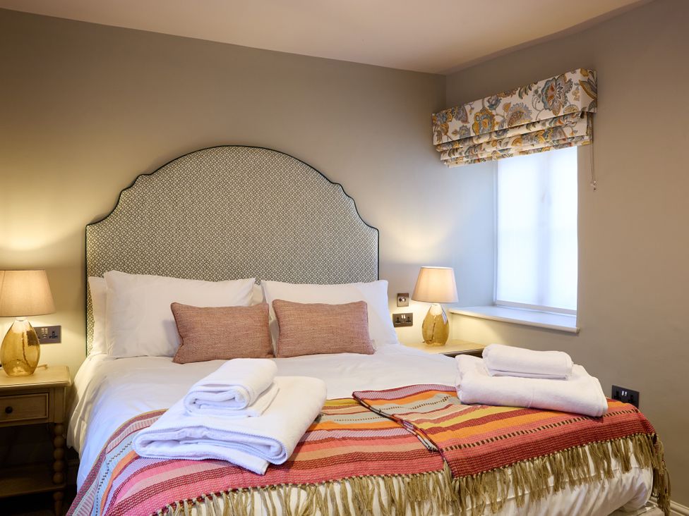 A bedroom with a bed and bedside lamps at Butler's Quarters in Matlock