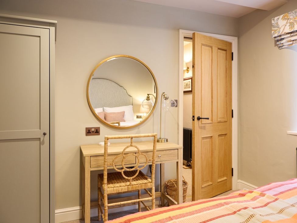 A bedroom with a mirror and desk at Butler's Quarters in Matlock