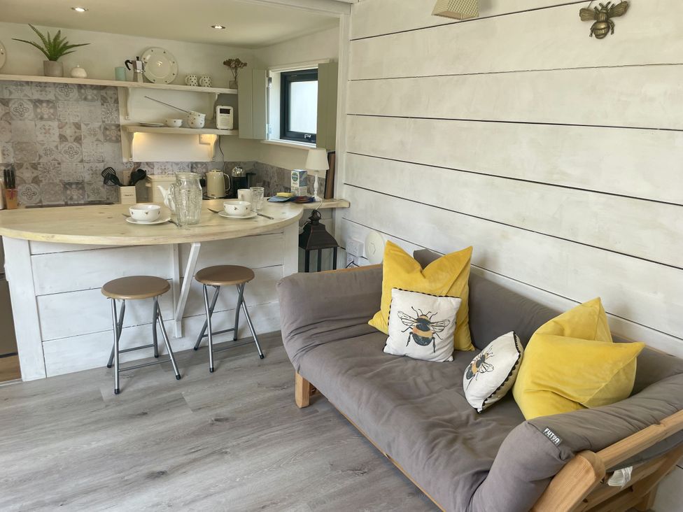 A kitchen with a counter and stools at The Cow Shed in Mawgan Porth