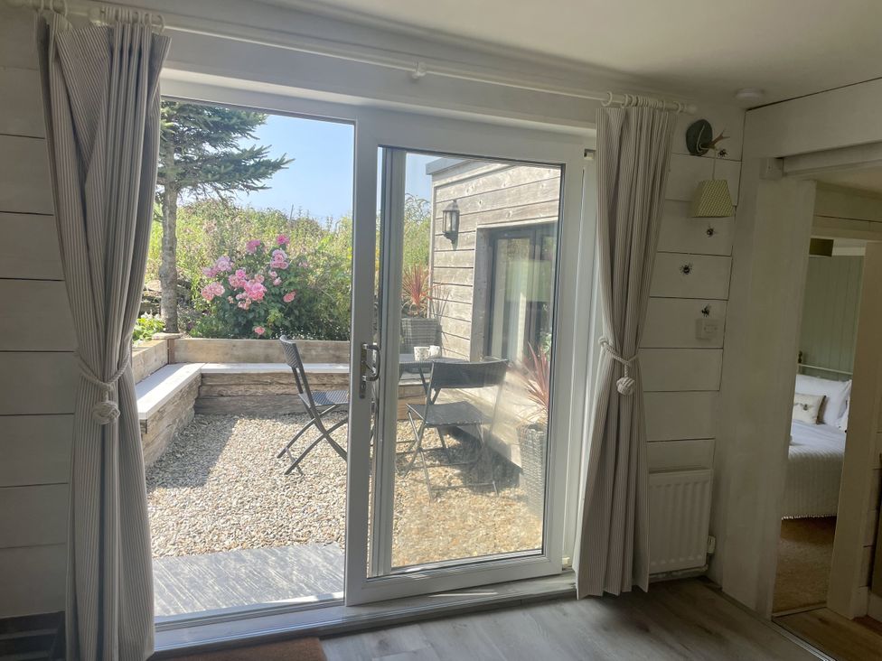 A living room with a view of the garden at The Cow Shed in Mawgan Porth