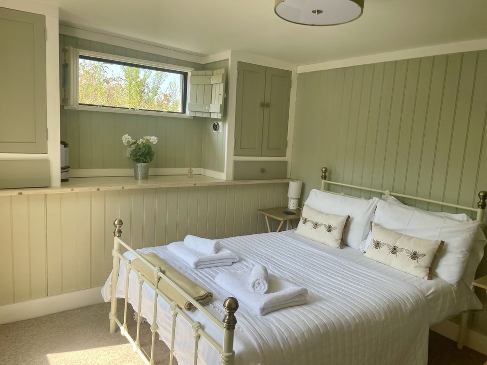 A bedroom with a bed and a lamp at The Cow Shed in Mawgan Porth