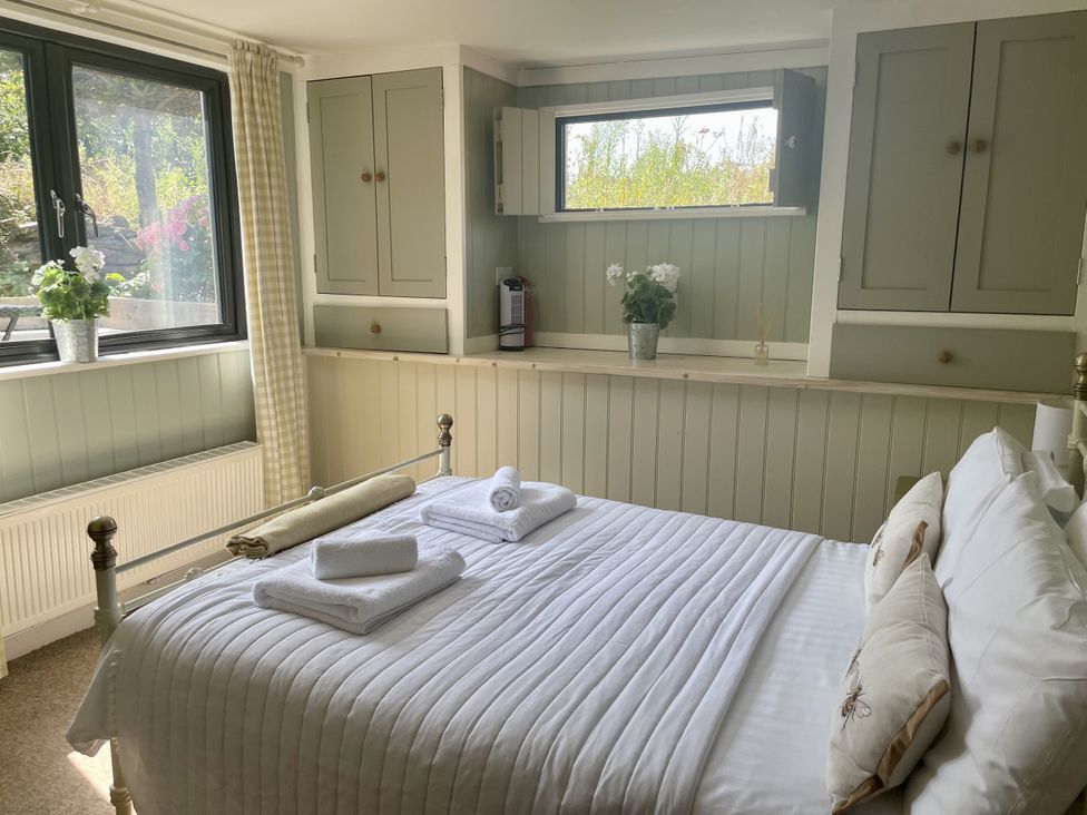 A bedroom with a bed and window at The Cow Shed in Mawgan Porth