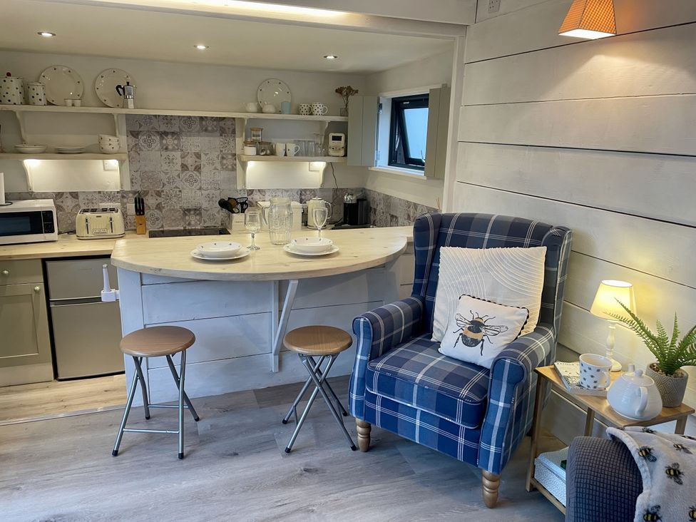 A kitchen with a counter and stools at The Cow Shed in Mawgan Porth