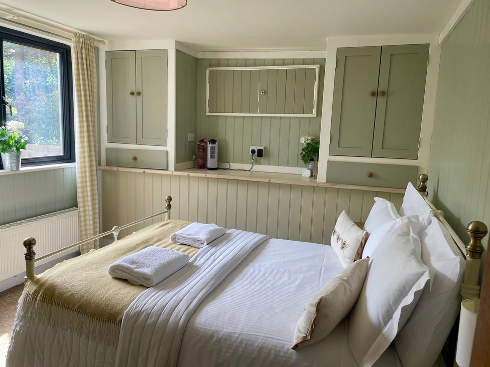 A bedroom with a bed and cabinets at The Cow Shed in Mawgan Porth