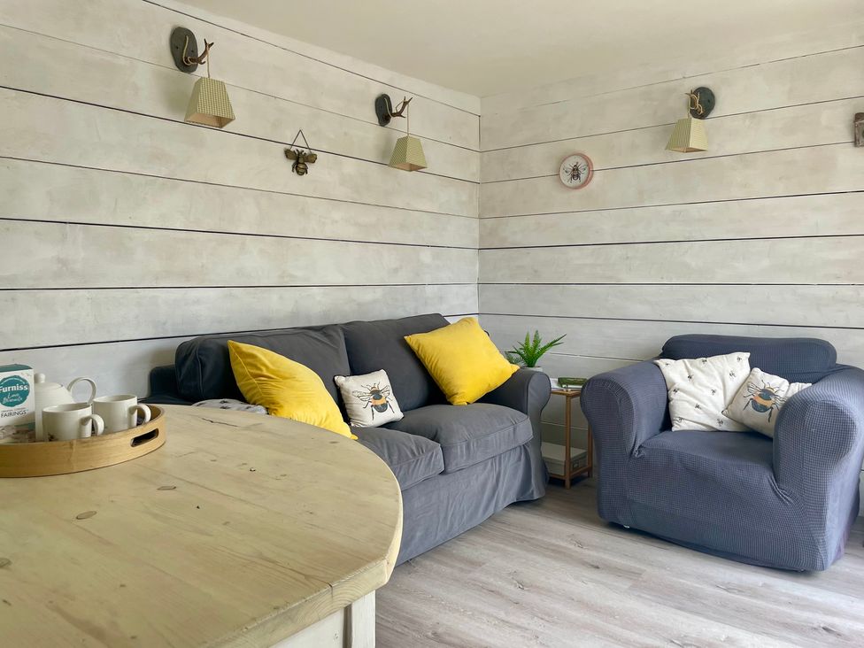 A snug with a sofa and an armchair at The Cow Shed in Mawgan Porth