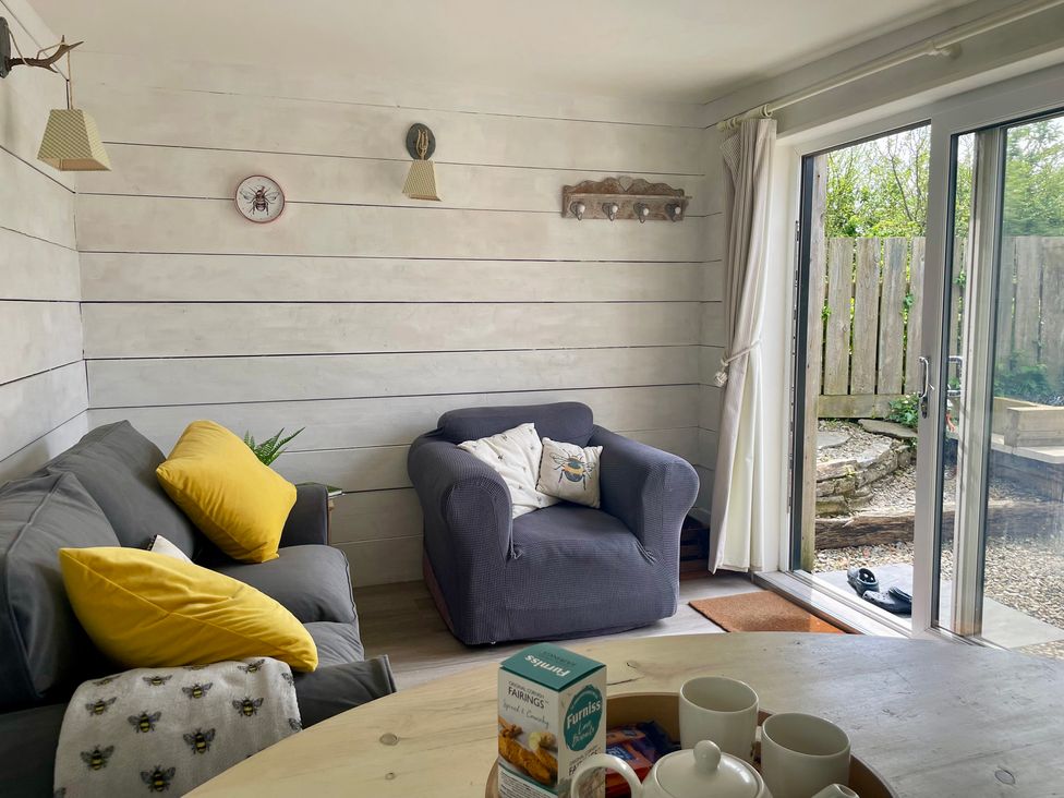 A living room with a sofa and armchair at The Cow Shed in Mawgan Porth