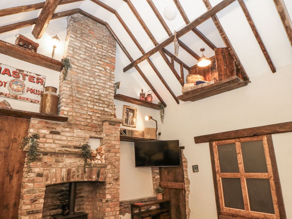 A living room with a brick fireplace and wooden beams at Dotty's Den in Bridlington