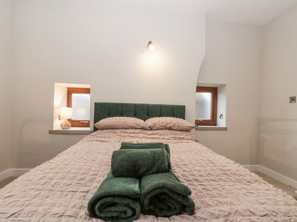 A bedroom with a green bed and towels folded at Dotty's Den in Bridlington
