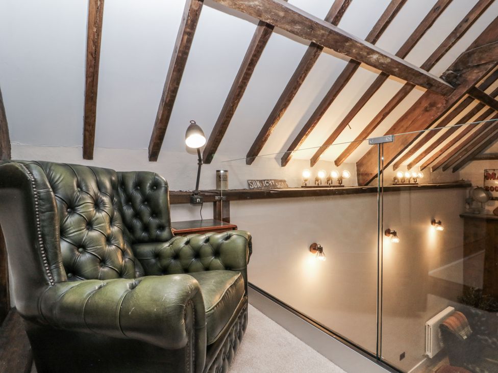 A loft area with an armchair and wall lights at Dotty's Den in Bridlington