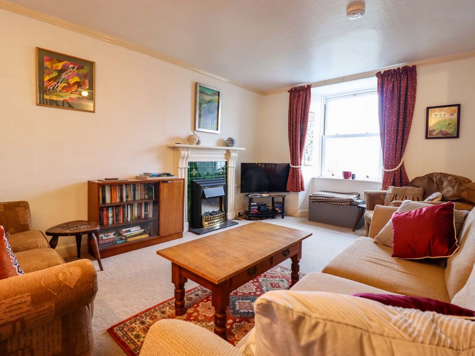 A living room with a sofa, coffee table, and bookshelf at Garth Celyn in Porthmadog