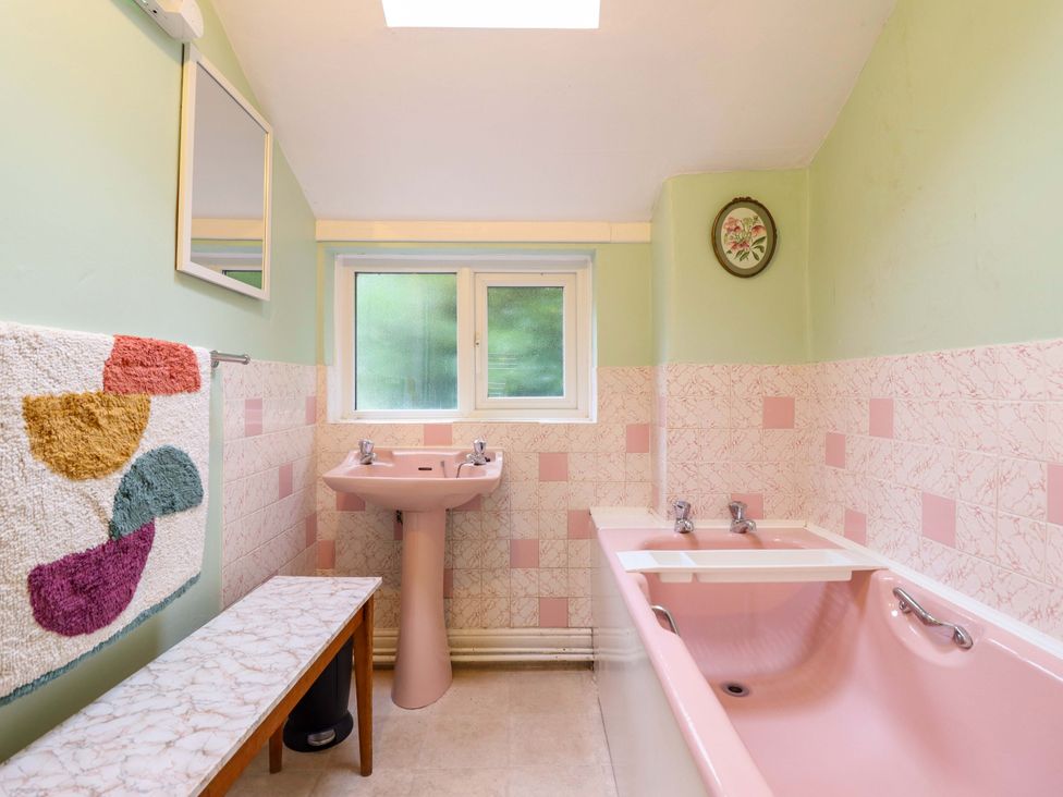 A bathroom with a pink bath and sink at Garth Celyn in Porthmadog