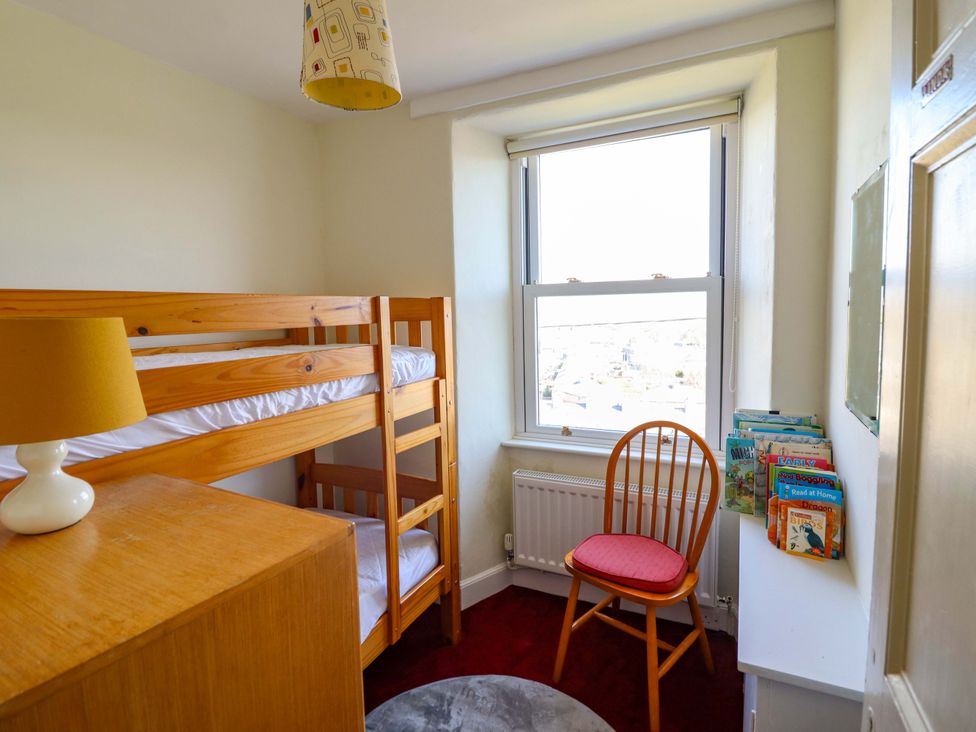 A bedroom with a bunk bed and a chair at Garth Celyn in Porthmadog