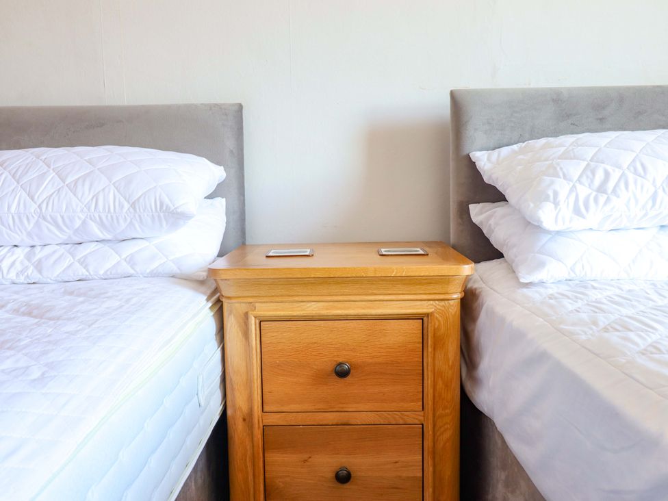 A bedroom with two beds and a bedside table at Garth Celyn in Porthmadog