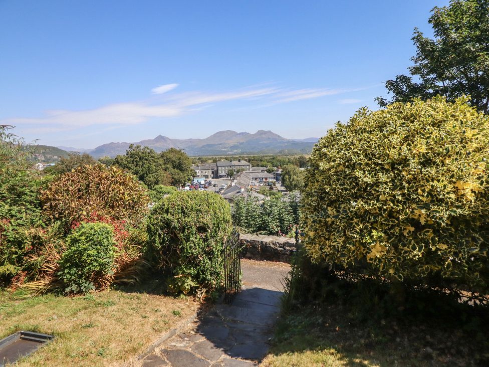 A garden with bushes and mountains in the background at Garth Celyn in Porthmadog