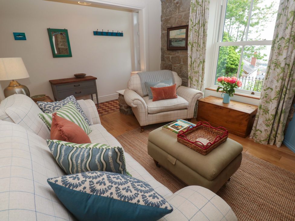 A living room with a sofa, chair, and coffee table at Kittiwake in Penzance
