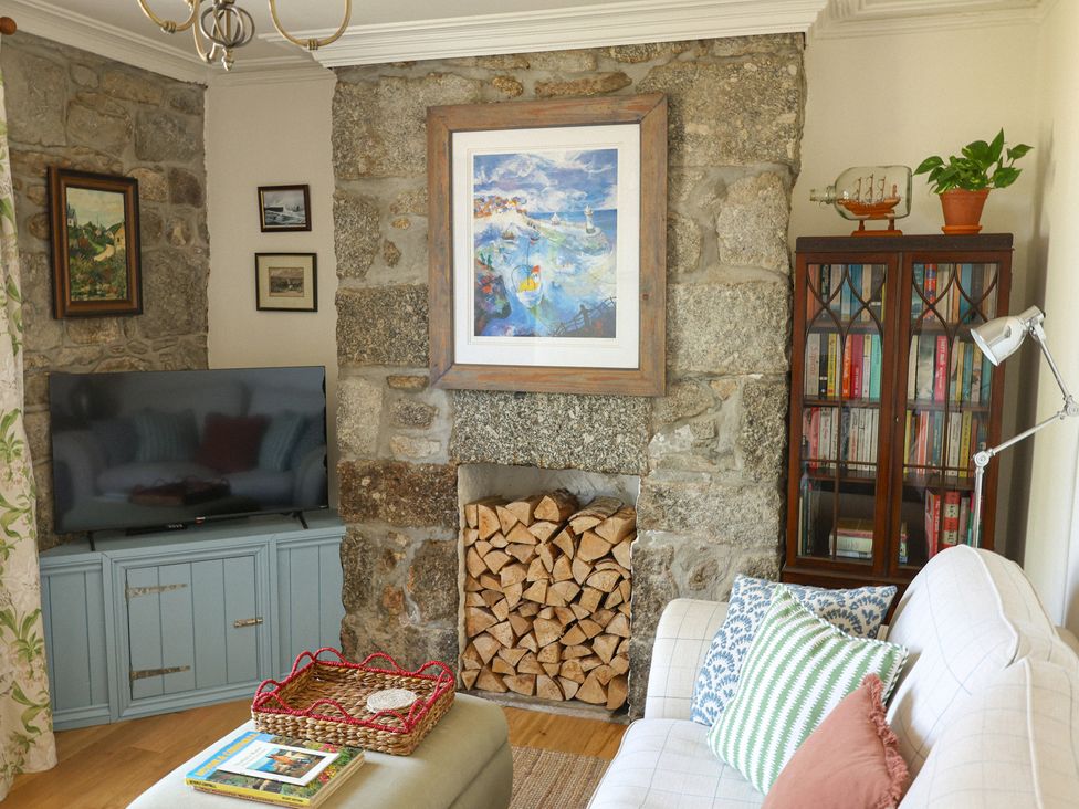 A living room with a television and a stone wall at Kittiwake Newlyn