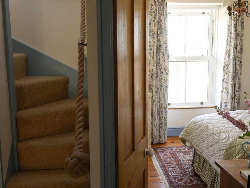 A bedroom with a staircase and window at Kittiwake in Newlyn