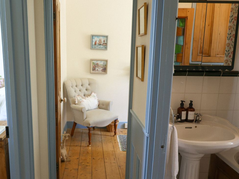 A bathroom with a sink and an armchair at Kittiwake Newlyn