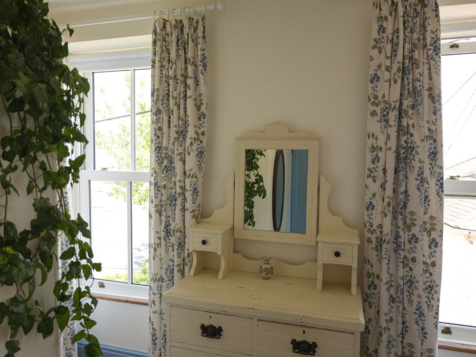 A dresser with a mirror and curtains in a bedroom at Kittiwake in Newlyn