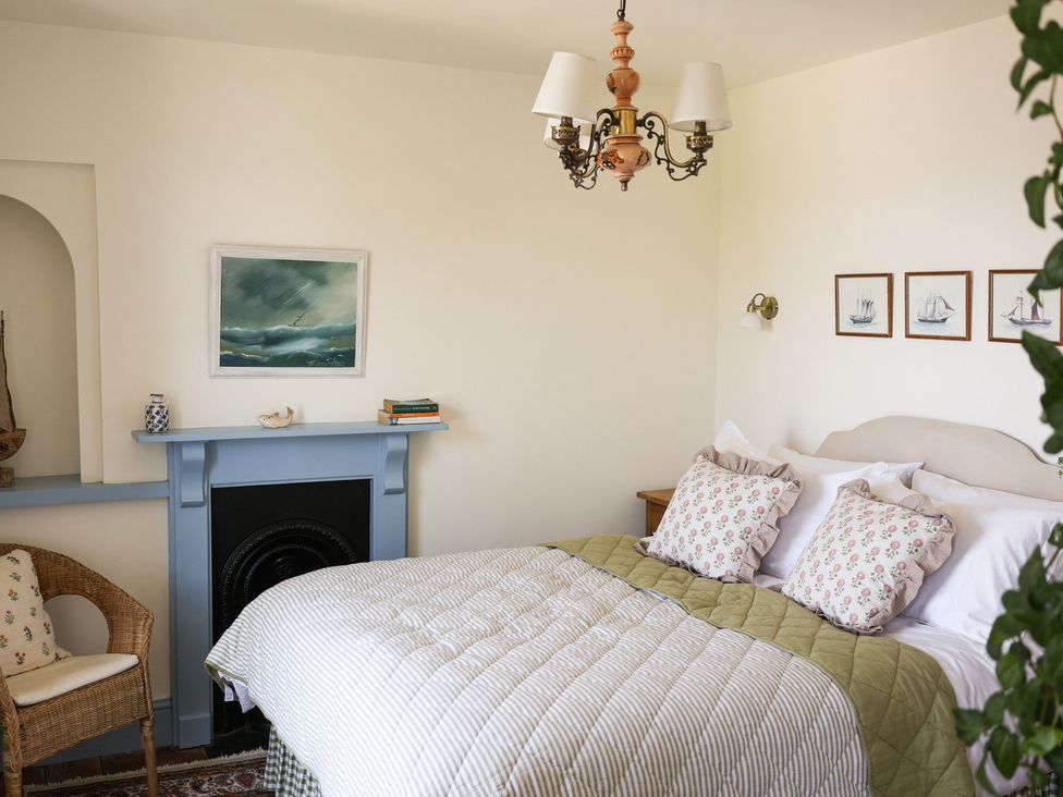 A bedroom with a bed, pillows, and artwork at Kittiwake in Newlyn