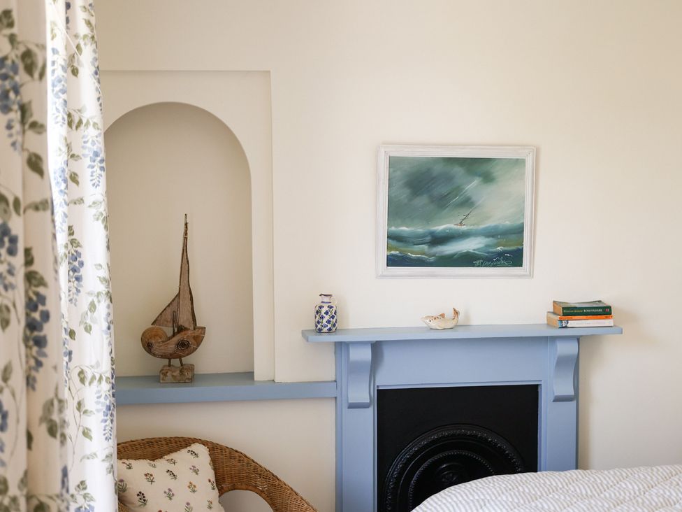 A bedroom with a painting, decorative items, and a sailing boat at Kittiwake in Newlyn