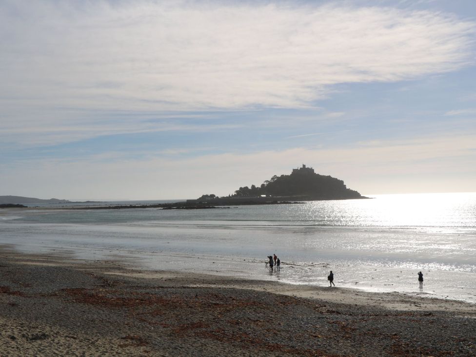 A beach scene with people walking by the water at Kittiwake in Newlyn