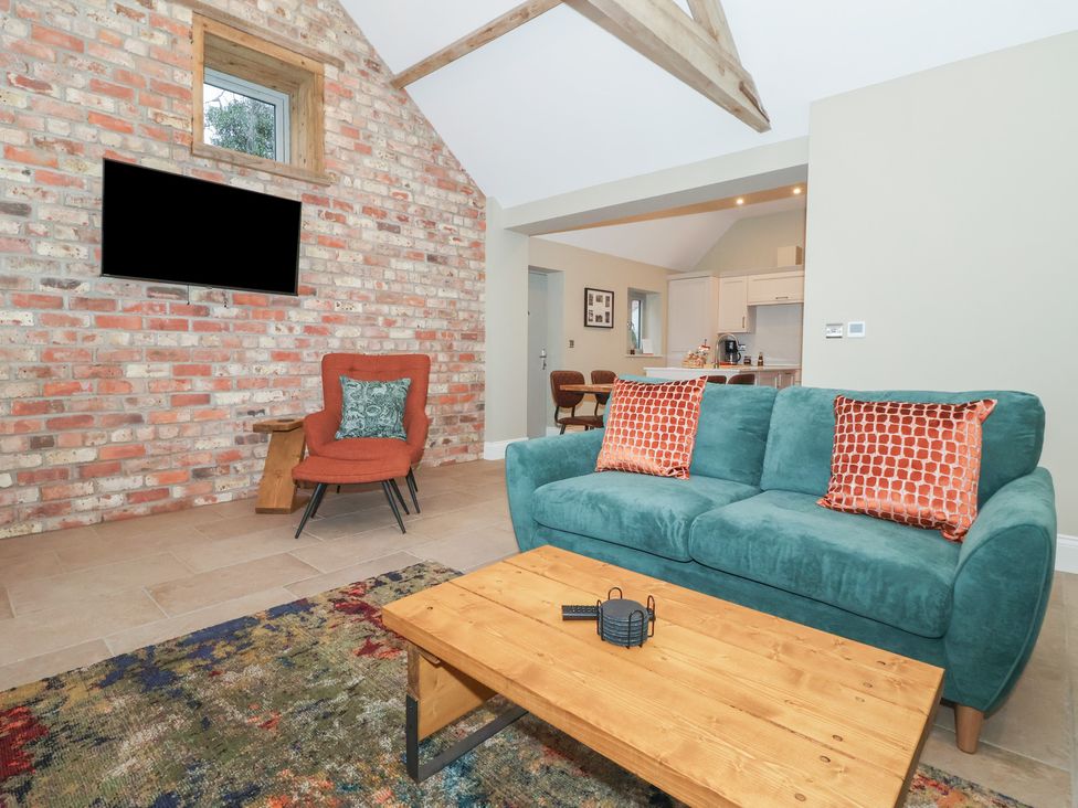 A living room with a blue sofa and wooden coffee table at Stable End Cottage York