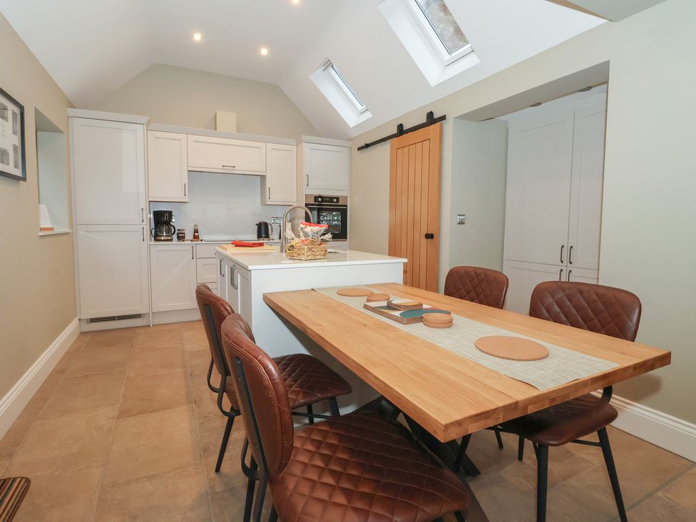 A kitchen with cabinets and a dining table at Stable End Cottage in York