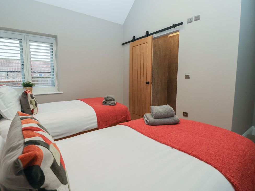 A bedroom with two beds and a sliding door at Stable End Cottage, York
