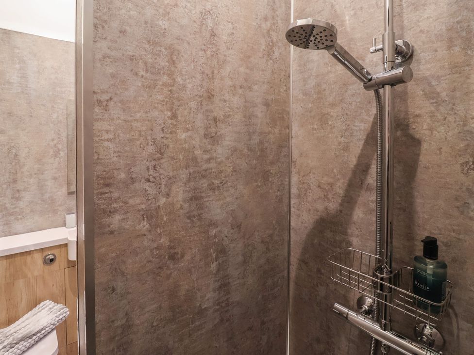 A shower area with a towel and soap dispenser at Stable End Cottage in York
